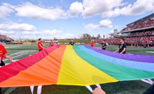 Image of fans holding a rainbow Pride flag on the field
