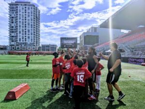 Image of players and kids training on the field at TD Place