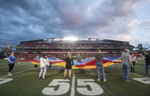 Image of fans holding a pride flag on the field during the national anthem