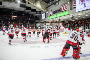 Image of 67's players celebrating on the ice after the game raising their sticks to the crowd